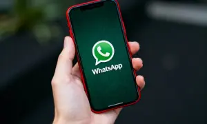 Dłoń trzyma smartfon z zielonym ekranem i logo WhatsApp. Dowiedz się, jak zaktualizować WhatsApp, aby korzystać z najnowszych funkcji.