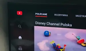 Ekran telewizora z aplikacją YouTube. Widoczne logo YouTube, menu "Polecane", "Rozrywka", "Muzyka" oraz kanał "Disney Channel Polska". Dowiedz się, jak zaktualizować aplikację YouTube.