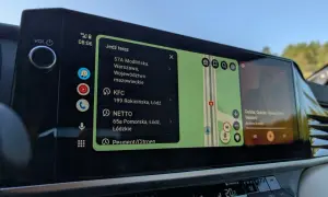 Na ekranie samochodu widać **android auto aplikacje**: nawigację z trasą, listę miejsc (KFC, NETTO) i odtwarzacz muzyki.