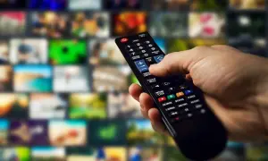 Dłoń trzymająca pilot do telewizora Samsung, gotowa do wykonania aktualizacji. Tło to mozaika ekranów.