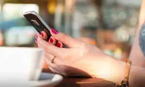 Kobieta z pomalowanymi paznokciami trzyma telefon, szukając informacji, jak zmienić dźwięk wiadomości w Messengerze.