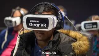 Osoba w goglach Samsung Gear VR, zastanawia się jakie gogle VR do telefonu wybrać. W tle inne osoby w podobnym sprzęcie.