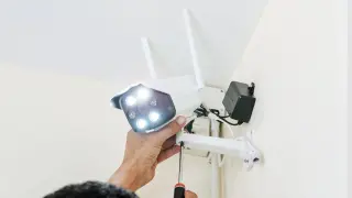 Montaż kamery zewnętrznej wifi. Ręka dokręca śrubę mocującą kamerę do uchwytu.
