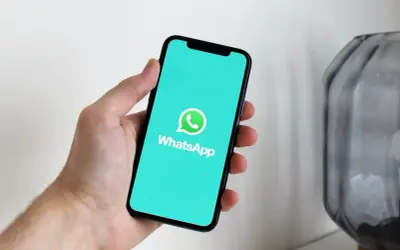Dłoń trzyma smartfon z włączoną aplikacją WhatsApp. Widzisz, jak działa WhatsApp w telefonie, dzięki czemu możesz łatwo rozmawiać z bliskimi.