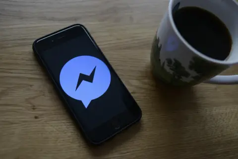 Telefon z ikoną Messengera na ekranie. Dowiedz się, jak ustawić dźwięk powiadomienia Messenger, by nie przegapić ważnych wiadomości.