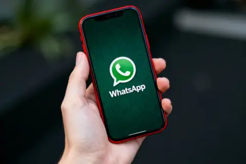 Dłoń trzyma smartfon z zielonym ekranem i logo WhatsApp. Dowiedz się, jak zaktualizować WhatsApp, aby korzystać z najnowszych funkcji.