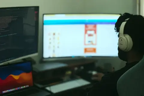 Programista w słuchawkach pracuje nad kodem w C++, widoczny jest ekran z kodem i interfejsem.