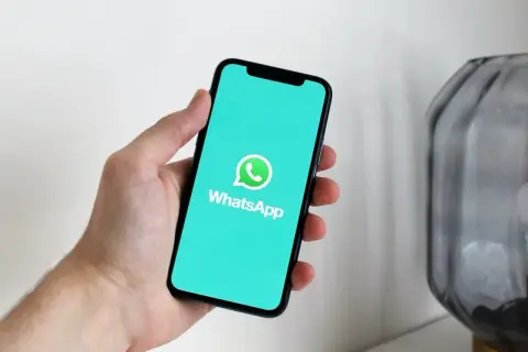 Dłoń trzyma smartfon z włączoną aplikacją WhatsApp. Widzisz, jak działa WhatsApp w telefonie, dzięki czemu możesz łatwo rozmawiać z bliskimi.