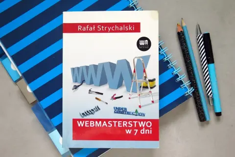 Książka "Webmasterstwo w 7 dni" Rafała Strychalskiego, która pomoże Ci dowiedzieć się, jak otworzyć plik HTML. Obok leżą przybory do pisania i notatnik.