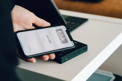 Dłoń trzyma smartfon z aplikacją Blik. Dowiedz się, jak zmienić limit Blik PeoPay.