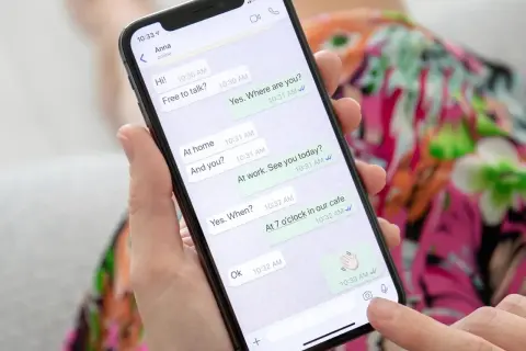 Dłoń trzyma smartfon z otwartym WhatsAppem, pokazującym rozmowę. To może być pomocne, gdy uczysz się, jak założyć WhatsApp krok po kroku.