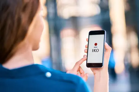 Kobieta z nowym telefonem, na ekranie którego widnieje logo aplikacji IKO. Szybko dowiesz się, jak zalogować się do aplikacji IKO na nowym telefonie.