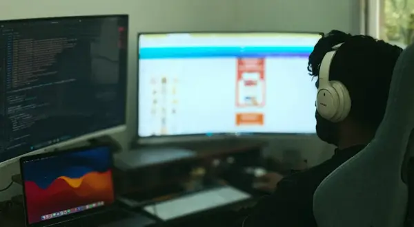 Programista w słuchawkach pracuje nad kodem w C++, widoczny jest ekran z kodem i interfejsem.