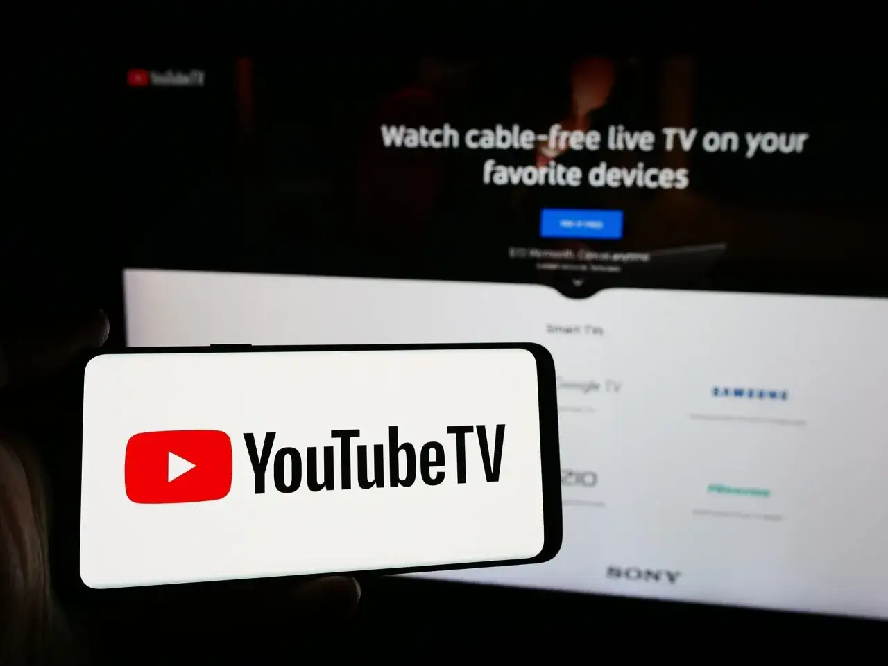 Smartfon z logo YouTube TV na ekranie. Obok ekran telewizora z napisem 