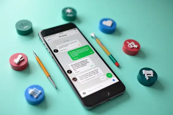 Telefon z otwartym WhatsAppem, otoczony kolorowymi symbolami. Dowiedz się, jak odświeżyć WhatsApp i usprawnić komunikację.