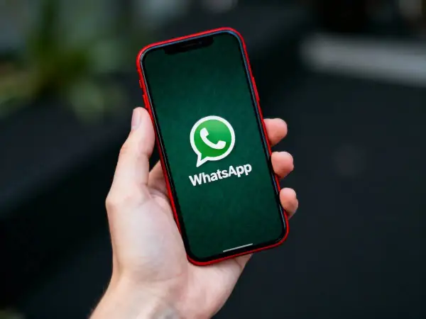 Dłoń trzyma smartfon z zielonym ekranem i logo WhatsApp. Dowiedz się, jak zaktualizować WhatsApp, aby korzystać z najnowszych funkcji.