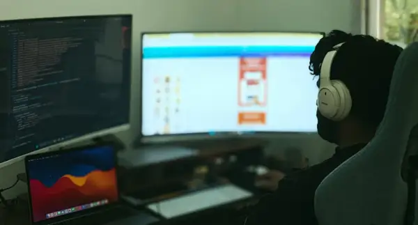 Programista w słuchawkach pracuje nad kodem w C++, widoczny jest ekran z kodem i interfejsem.