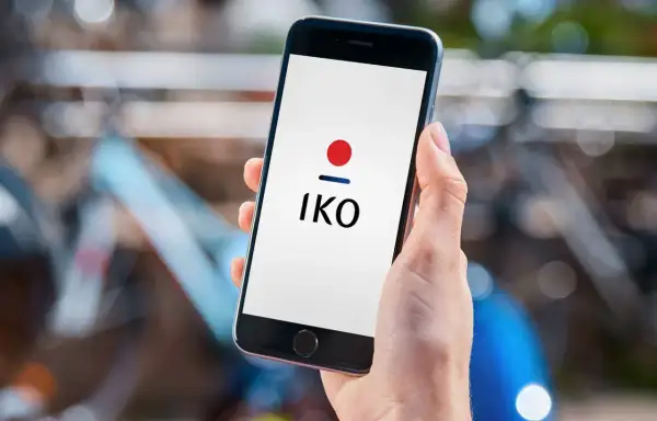 Dłoń trzyma smartfon z logo IKO. Dowiedz się, jak założyć IKO w telefonie, by wygodnie płacić.