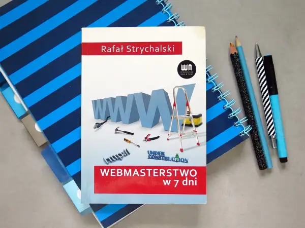 Książka "Webmasterstwo w 7 dni" Rafała Strychalskiego, która pomoże Ci dowiedzieć się, jak otworzyć plik HTML. Obok leżą przybory do pisania i notatnik.