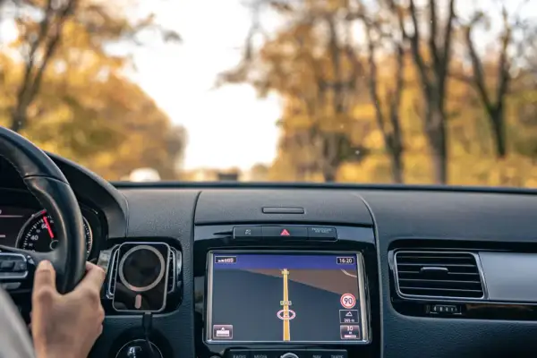 Widok z wnętrza samochodu na nawigację GPS. Kierowca trzyma kierownicę, a ekran pokazuje trasę. To dobry moment, by pomyśleć, jak zaktualizować GPS.