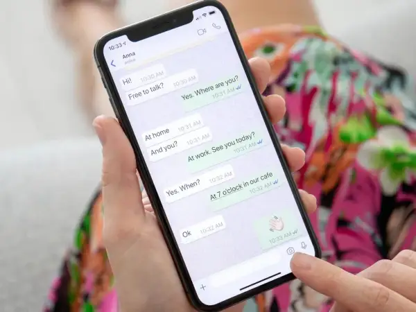 Dłoń trzyma smartfon z otwartym WhatsAppem, pokazującym rozmowę. To może być pomocne, gdy uczysz się, jak założyć WhatsApp krok po kroku.